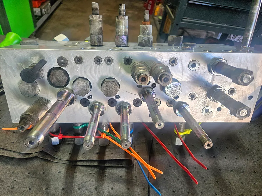 Hydraulic manifold and valve components laid out during a rebuild