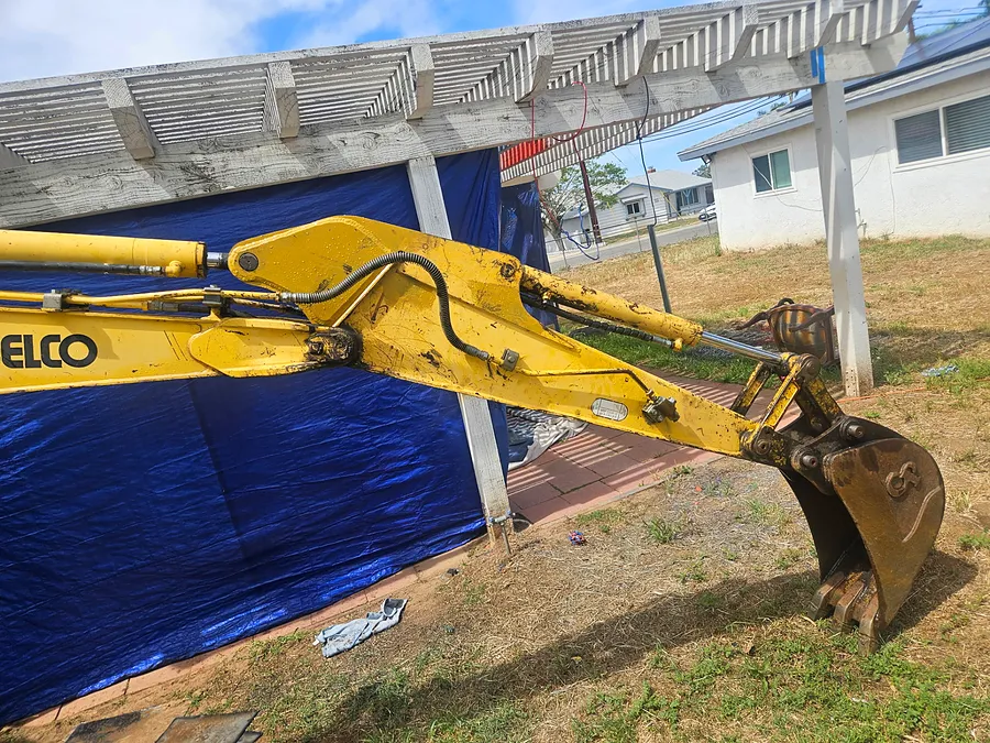 Excavator boom, cylinder, and bucket staged for repair