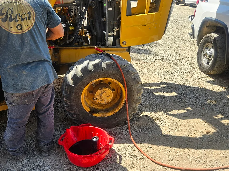 Technician working on an open loader engine compartment at a jobsite